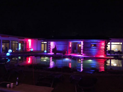 Saunalandschaft Beleuchtetes Schwimmbad mit bunten Lichtern bei Nacht.