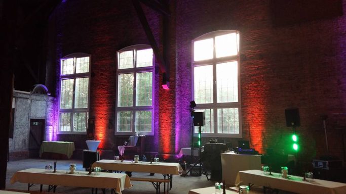 Aufbau Lokhalle Ein heller Veranstaltungsraum mit bunten Lichtern und großen Fenstern.