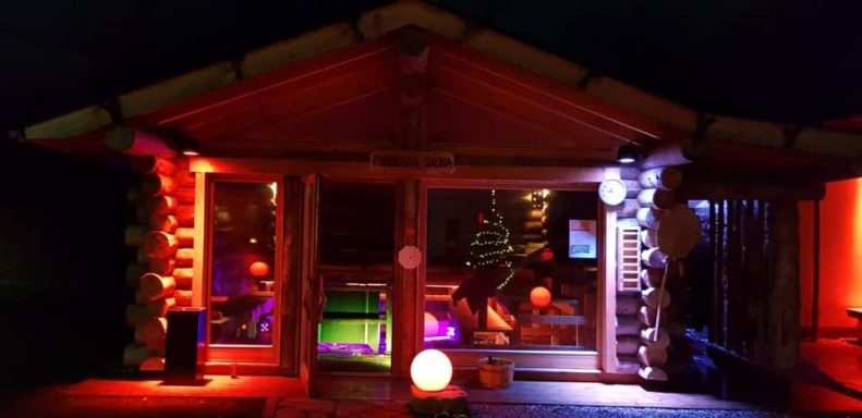 Saunalandschaft Buntbeleuchtete Holzhütte mit festlicher Dekoration und gemütlicher Atmosphäre.