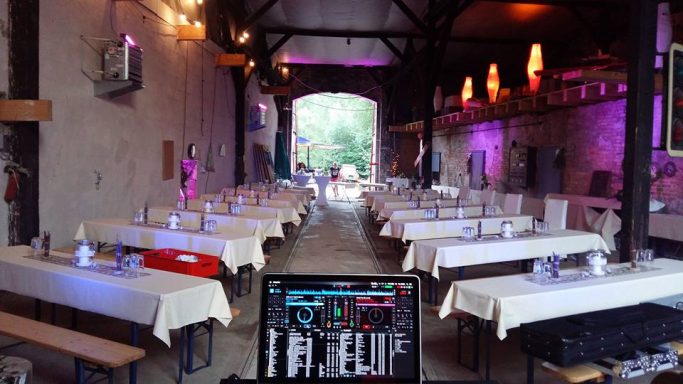 Aufbau Lokhalle Innenansicht eines festlich dekorierten Veranstaltungsraums mit langen Tischen und bunten Lichtern.